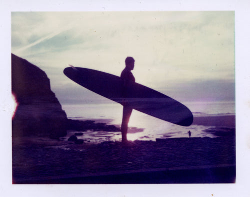 Polaroid image of a Silhouette of a surfer at sunset 