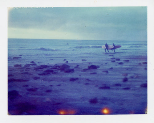 Polaroid of distant longboarders at Porthtowan